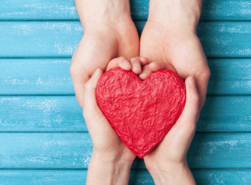 Woman and man hands holding red shape of heart. Saint valentine day background. Relationship, family and donorship concept.
